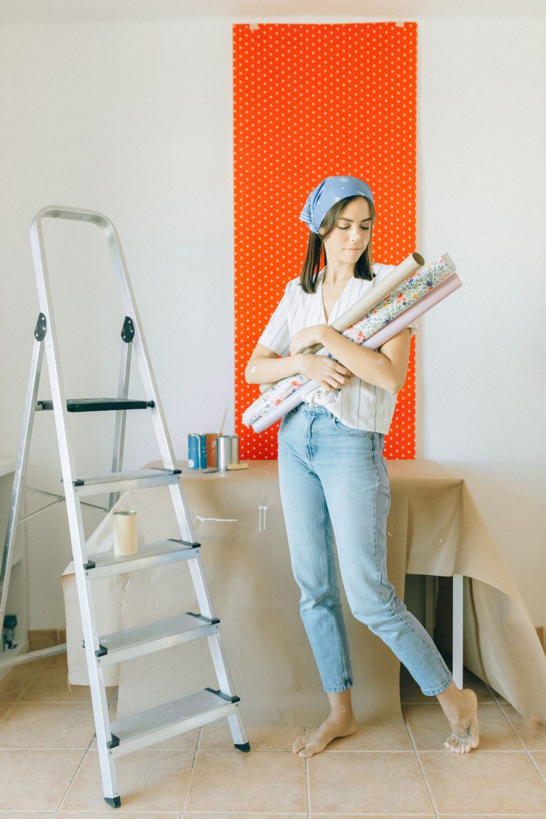 Renter holding a roll of peel and stick wallpaper against an apartment wall