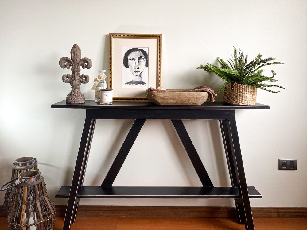 Two framed prints leaning against a wall on a wooden console table